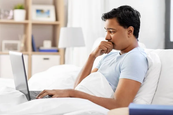 Hombre indio preocupado con el ordenador portátil en la cama en casa — Foto de Stock