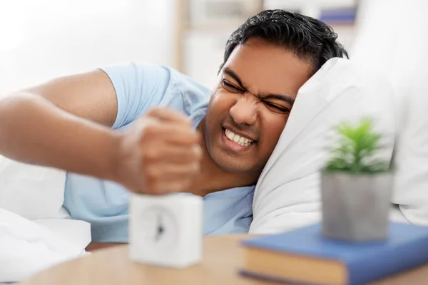 Сердитый индиец с будильником в постели — стоковое фото