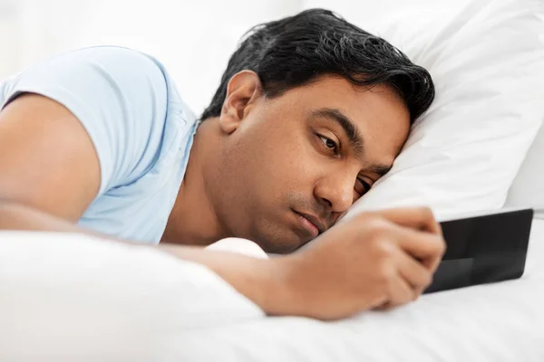 Akıllı telefonlu uykulu Hintli adam yatakta yatıyor. — Stok fotoğraf