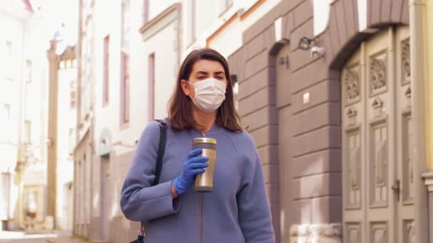 Γυναίκα με ιατρική μάσκα με tumbler περπάτημα στην πόλη — Αρχείο Βίντεο