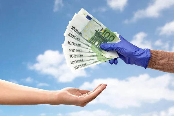 Egyik kéz az orvosi kesztyűben pénzt ad a másiknak. — Stock Fotó