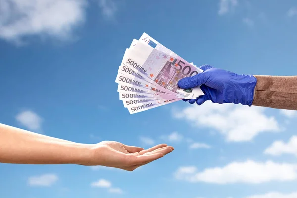 Una mano en guante médico dando dinero a otra — Foto de Stock