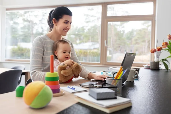 Мати з дитиною і ноутбуком працює в домашньому офісі — стокове фото
