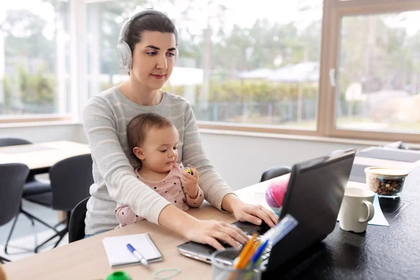 Мати з дитиною працює на ноутбуці в домашньому офісі — стокове фото