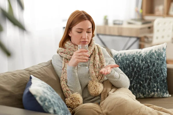 Mulher doente tomando remédio com água em casa — Fotografia de Stock