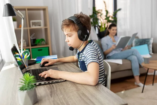 Garçon avec ordinateur portable et écouteurs à la maison — Photo