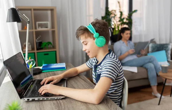 Мальчик с ноутбуком и наушниками дома — стоковое фото