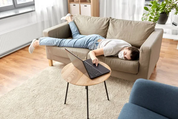 Mujer aburrida enferma con el ordenador portátil acostado en el sofá en casa —  Fotos de Stock
