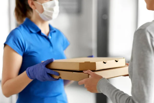 Entrega menina em máscara dando caixas de pizza para mulher — Fotografia de Stock