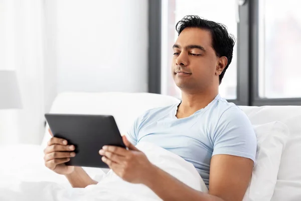 Gelukkig indisch man met tablet pc in bed thuis — Stockfoto