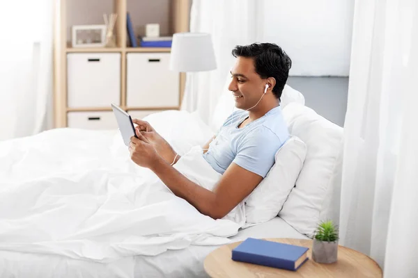 Gelukkig indisch man met tablet pc in bed thuis — Stockfoto