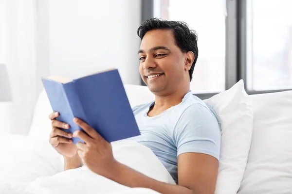 Heureux homme indien lecture livre dans le lit à la maison — Photo