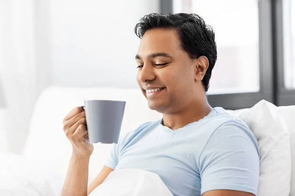 Gelukkig indiaanse man drinken koffie in bed thuis — Stockfoto