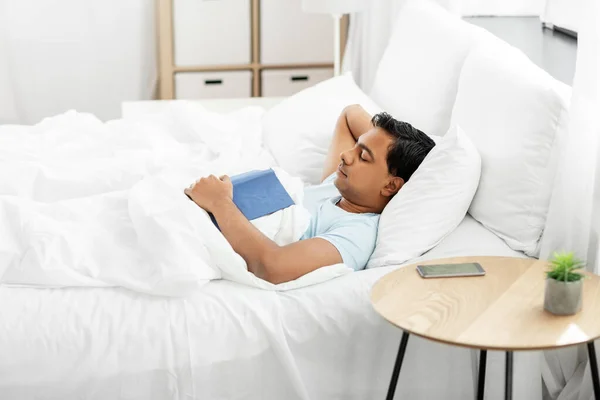 Hombre indio con libro durmiendo en la cama en casa —  Fotos de Stock