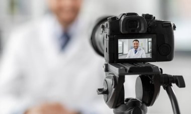 male doctor recording video blog at hospital clipart