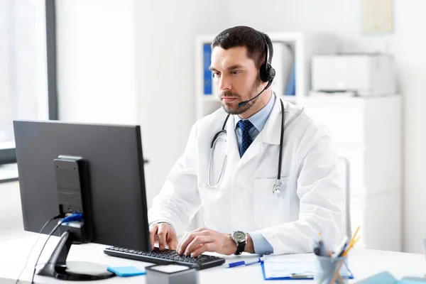 Médico masculino com computador e fone de ouvido no hospital — Fotografia de Stock