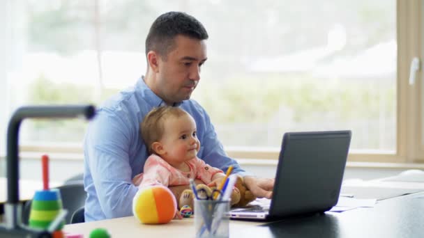 Padre con el bebé trabajando en el ordenador portátil en la oficina en casa — Vídeo de stock