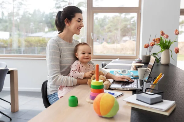 Madre con el bebé y el ordenador portátil trabajando en la oficina en casa — Foto de Stock