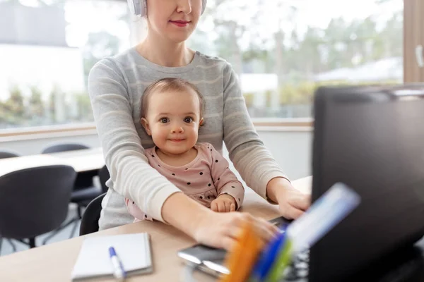 Мати з дитиною працює на ноутбуці в домашньому офісі — стокове фото
