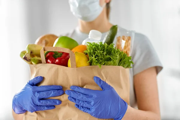 Mujer en guantes con comida en bolsa de papel en casa — Foto de Stock