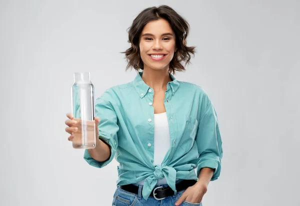 Leende ung kvinna håller vatten i glasflaska — Stockfoto