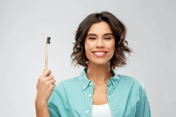 Sorrindo jovem mulher com escova de dentes de madeira — Fotografia de Stock