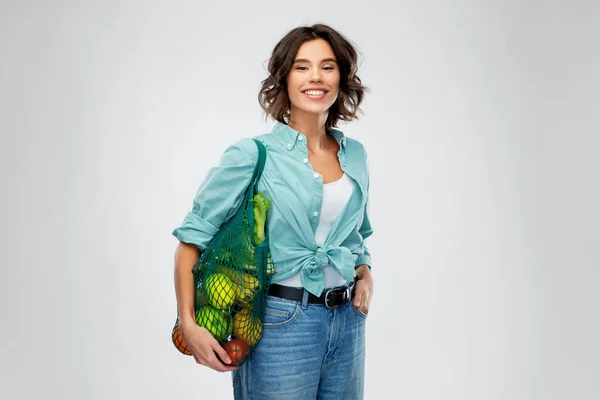 Mujer sonriente feliz con comida en bolsa de red reutilizable — Foto de Stock