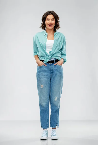 Lächelnde junge Frau in türkisfarbenem Hemd und Jeans — Stockfoto