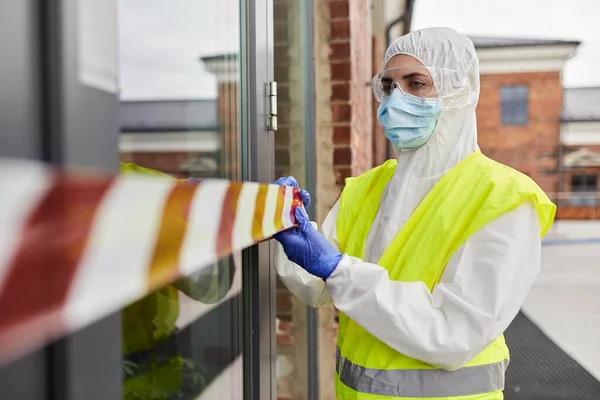 Healthcare worker sealing door with caution tape — Stock Photo, Image