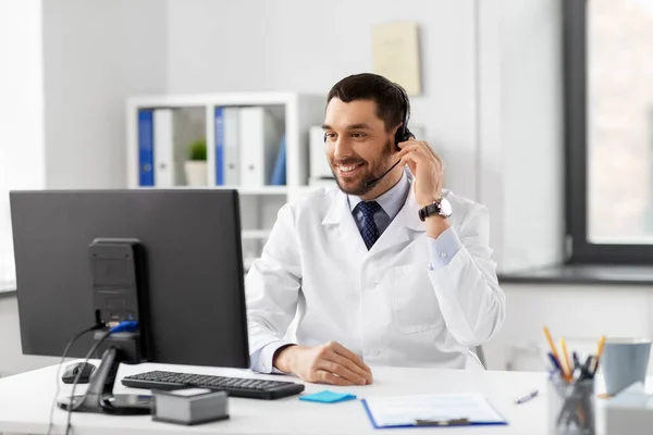 Happy doctor with computer and headset at hospital — Stock Photo, Image