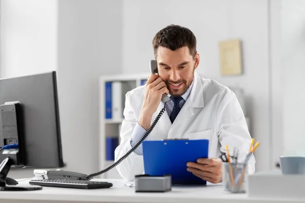 Médico masculino chamando no telefone mesa no hospital — Fotografia de Stock
