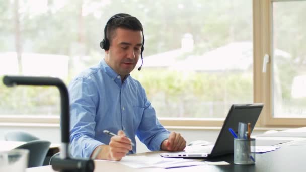 Man met headset en laptop thuis aan het werk — Stockvideo