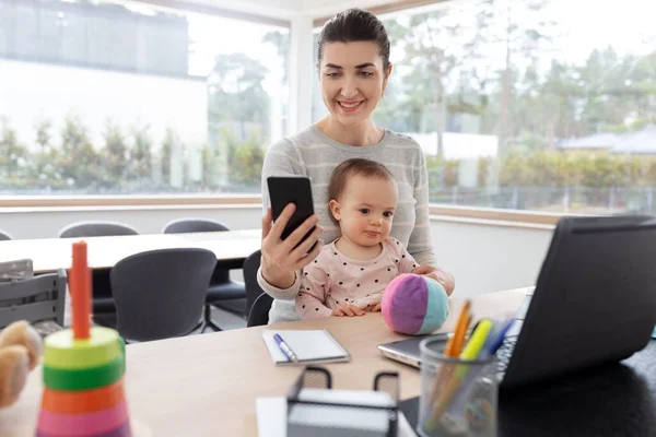 Mãe com bebê e telefone trabalhando no escritório em casa — Fotografia de Stock