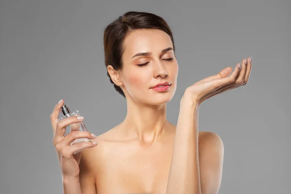 Šťastná žena vonící parfém z jejího zápěstí — Stock fotografie