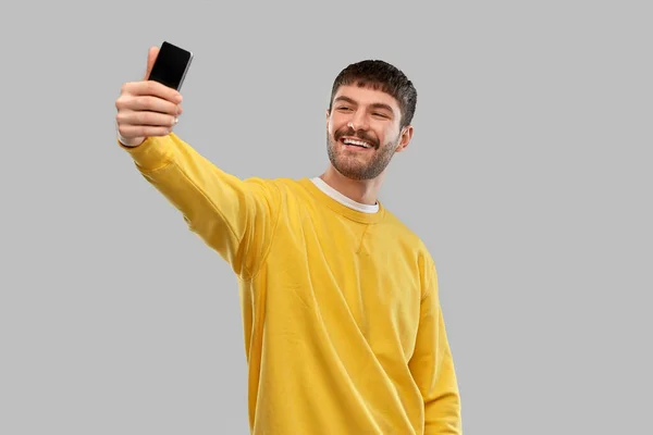 Smiling young man taking selfie with smartphone — Stock Photo, Image