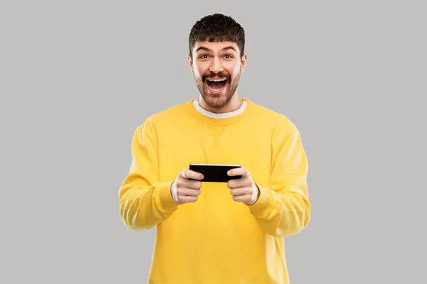 Glücklich lachender junger Mann mit Smartphone — Stockfoto