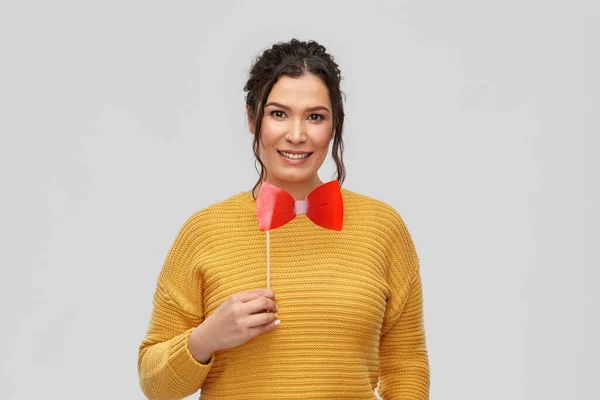 Happy young woman with big red bowtie party prop — ストック写真