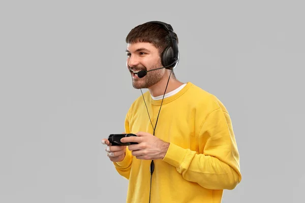 Uomo con auricolare e gamepad giocare al videogioco — Foto Stock