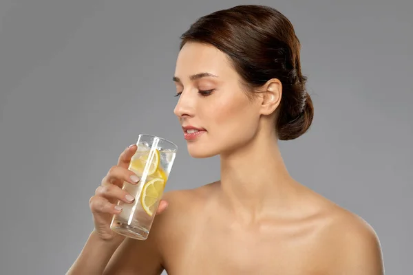 Frau trinkt Wasser mit Zitrone und Eis — Stockfoto