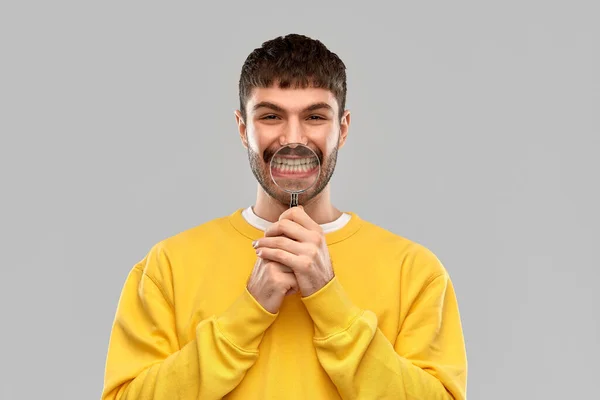 Uomo sorridente con lente di ingrandimento che mostra i denti — Foto Stock