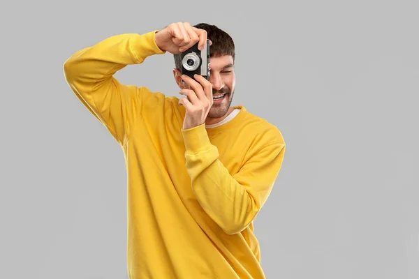 Счастливый улыбающийся молодой человек с винтажной кинокамерой — стоковое фото