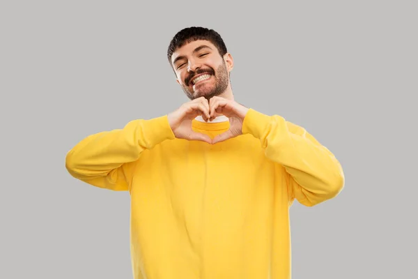 Hymyilevä nuori mies keltaisessa puserossa — kuvapankkivalokuva