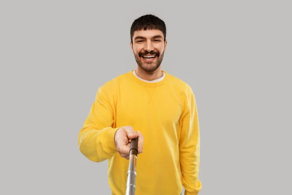 Happy young man taking picture with selfie stick — Φωτογραφία Αρχείου