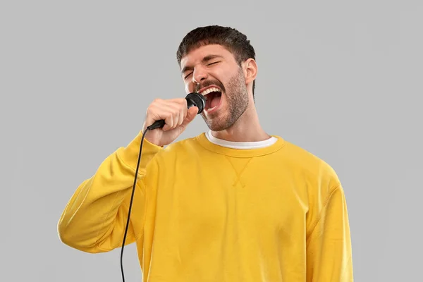 Muž ve žluté mikině se zpěvem mikrofonu — Stock fotografie