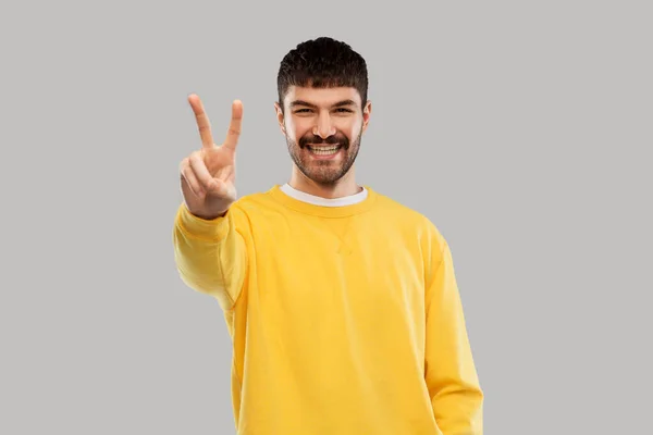 Young man showing peace over grey background — Stock Photo, Image