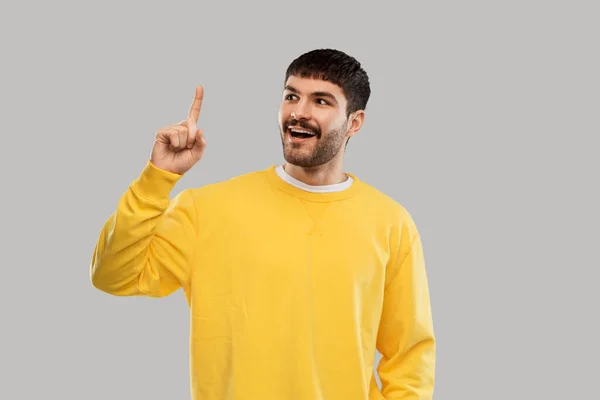 Young man showing one finger in yellow sweatshirt — Stockfoto