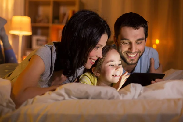 Familia con tableta pc en la cama por la noche en casa —  Fotos de Stock