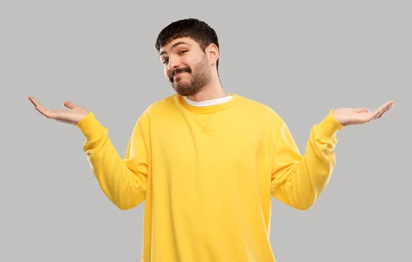 Confused man in yellow sweatshirt shrugging — ストック写真