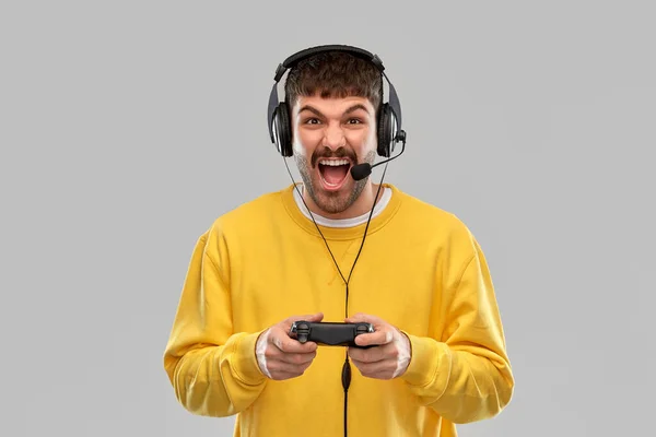 Hombre con auriculares y gamepad jugando videojuego —  Fotos de Stock