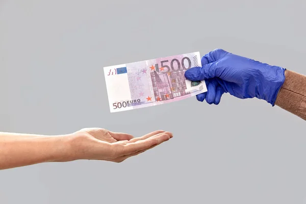 Szoros kéz a kézben orvosi kesztyű ad pénzt — Stock Fotó